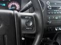 Close-up of a steering wheel in a 2015 Ford F-450 featuring control buttons for media and volume on the left side