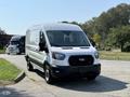 A 2022 Ford Transit van in a sleek white color with a black grille and large headlights positioned at an angle on a road