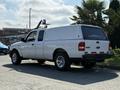 A white 2009 Ford Ranger pickup truck with a hard tonneau cover and chrome wheels parked on the side of the road