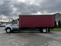 A white 2008 Ford F-750 truck with a red box trailer parked with a side view showing its length and sturdy build