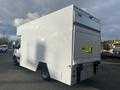 A 2017 Mercedes-Benz Sprinter van with a white exterior and a large cargo area at the back featuring a roll-up door and warning signs on the side