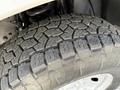 Close-up of a rugged tire featuring a deep tread pattern designed for off-road performance attached to a 2011 Ford F-250 SD