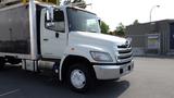 A white 2013 Hino 268 truck with a metal box cargo bed and chrome front grille parked with the cab facing forward