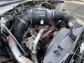 Engine of a 2011 Ford F-750 featuring a large black air intake hose and visible components like the alternator and coolant reservoir