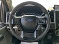 Steering wheel of a 2018 Ford F-550 with controls for audio and cruise settings and the Ford logo in the center