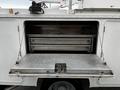 A utility compartment of a 2016 Ford F-550 with a metal folding door and sliding metal shelves inside