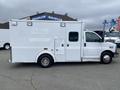 A white 2014 Chevrolet Express van converted into an ambulance with multiple exterior compartments and emergency lights on top