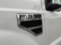 Close-up of a chrome badge on a white 2008 Ford F-350 XLT Super Duty truck displaying the model name and designation while wet from rain