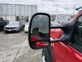 A red 2007 Ford F-550 with a side mirror reflecting its surroundings