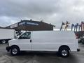 A white 2022 GMC Savana van with a long cargo area and chrome wheels, viewed from the side