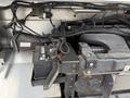 2012 Ford Econoline engine compartment showing the battery and various engine components with wires and tubing