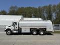 A 2009 International 7500 truck with a silver tanker body and dual rear axles is parked side view showcasing its large storage capacity and functional design