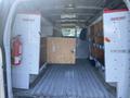 Interior view of a 2012 GMC Savana cargo van featuring shelves and wooden storage compartments along the sides and a fire extinguisher mounted on the left