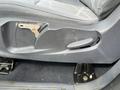 Close-up view of the driver's seat adjustment lever on a 2010 Ford Transit Connect showing the worn edge and textured surface of the seat