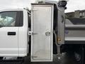 A 2021 Ford F-550 truck with an open metal storage compartment on the side featuring a round handle and lock