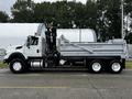 A 2017 International WorkStar 7600 truck with a gray dump bed and a hydraulic lift system mounted on the side