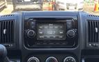 Dashboard of a 2016 RAM Promaster featuring a multimedia display with audio controls air conditioning knobs and various function buttons