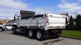 A white 2014 International 7500 dump truck with a black dump bed and dual rear wheels parked at a site