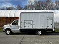 A 2013 Ford Econoline van with a white box truck body featuring a rear door and small side windows positioned on a concrete surface