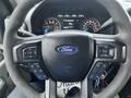 Steering wheel of a 2017 Ford F-150 featuring buttons for volume control and multimedia settings with a Ford emblem in the center