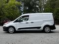 A white 2014 Ford Transit Connect van is parked sideways with a sleek body design and a black stripe along the side