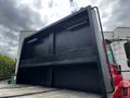 A 2011 International 4400 dump truck with a black dump bed raised, revealing the interior of the bed and its sturdy construction