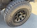 A close-up of a black alloy wheel on a 2010 Toyota Tacoma featuring a rugged tire with deep treads designed for off-road driving