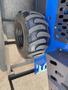 A close-up view of a black tire with deep treads mounted on a blue metal structure