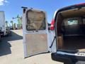 A 2012 Chevrolet Express van with the rear doors open, revealing its interior space with wooden flooring and a metal wall panel