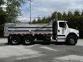 A 2010 Freightliner M2 106 dump truck featuring a silver dump bed with a hydraulic lift and a cab with side mirrors and large tires