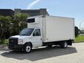 A 2023 Ford E-450 box truck with a white exterior and a refrigeration unit on top parked at an angle with the front visible