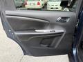 A 2013 Dodge Journey driver door interior featuring a matte black panel with armrest and control buttons for windows and locks