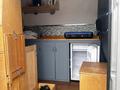 Interior of a 2010 Mercedes-Benz Sprinter featuring a kitchen area with a sink a refrigerator a stove and wooden cabinets