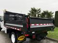 A 2022 Ford F-550 with a black dump bed and red reflective stripes featuring a company logo on the side