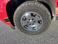 A close-up of a chrome alloy wheel with six circular holes mounted on a rugged tire featuring raised lettering on a Chevrolet Avalanche