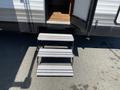 A set of four metal steps leading up to the entrance of a 2016 Jayco 265RLSW travel trailer