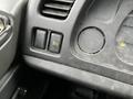 Close-up of the dashboard of a 2006 GMC F7B042 showing a power outlet a control switch and a circular gauge all with a dusty surface