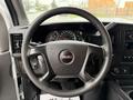 A close-up view of the steering wheel of a 2014 GMC Savana featuring the GMC logo and controls for audio and cruise settings on the wheel