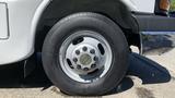 A close-up of a 2011 Chevrolet Express wheel featuring a silver rim with a central Chevrolet logo and a black tire with the brand name visible on the tread