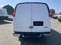 A 2016 GMC Savana white cargo van viewed from the rear showcasing a clean design with taillights and a hitch receiver