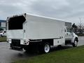 A white 2013 Ford F-650 truck with a boxy cargo area and red and orange lights on the back