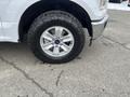 A white 2017 Ford F-150 with a close-up view of its chrome wheel and large all-terrain tire