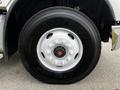 A close-up of a Goodyear tire mounted on a white Freightliner M2 112 truck with a chrome hubcap and lug nuts visible