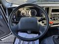 The image shows the steering wheel and dashboard of a 2020 Isuzu NPR with various gauges and controls visible