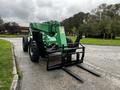 A green 2014 JLG 10054 telescopic forklift with extended forks and large black tires facing forward on a paved surface