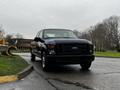 A black 2008 Ford F-250 SD parked on a street with a visible front view showcasing its large grille and rugged design