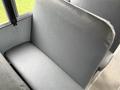 A grey vinyl seat in a bus with a smooth surface and padded backrest providing seating for passengers