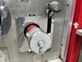 A chrome hose connection on a fire truck with a red rubber hose partially visible and a valve handle labeled to lock