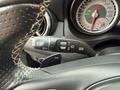 Close-up of a 2016 Mercedes-Benz GLA-250 steering wheel showing controls for wipers and headlights with a sporty design and detailed instrument gauge in the background