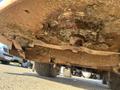 The image shows the underside of a 2010 Kubota F3990 mower deck with visible rust dirt and grass clippings accumulated around the blades and deck components